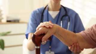 Caregiver supporting senior woman indoors, closeup. Home health care service